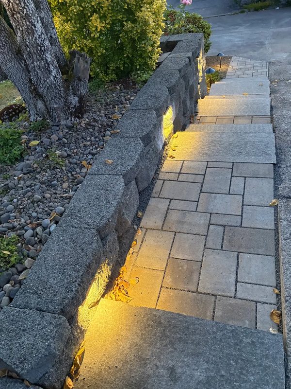 Paver walkway and steps lit by wall lights at dusk